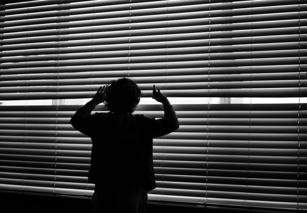 man looking through blinds